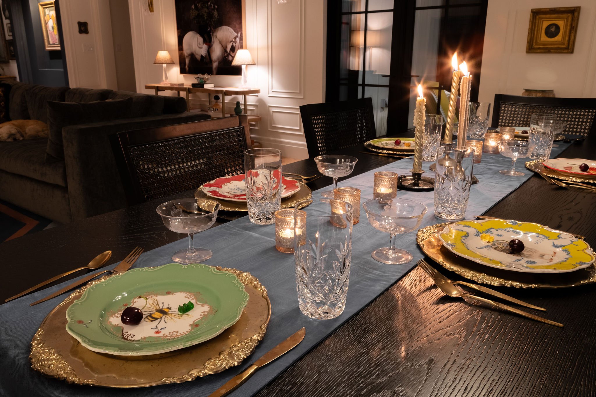 Candlelit dinner table with gold-rimmed plates, crystal glasses, and a blue linen runner